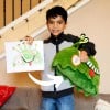 Thumbnail of a happy kids holding the drawing and a custom plushie made out of it by Child's Own Studio